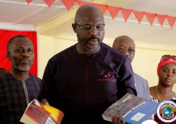 President Weah Inspects Books as the Minister McGill and Executive Mansion COP Finda Bundoo look on.EXECUTIVE MANSION